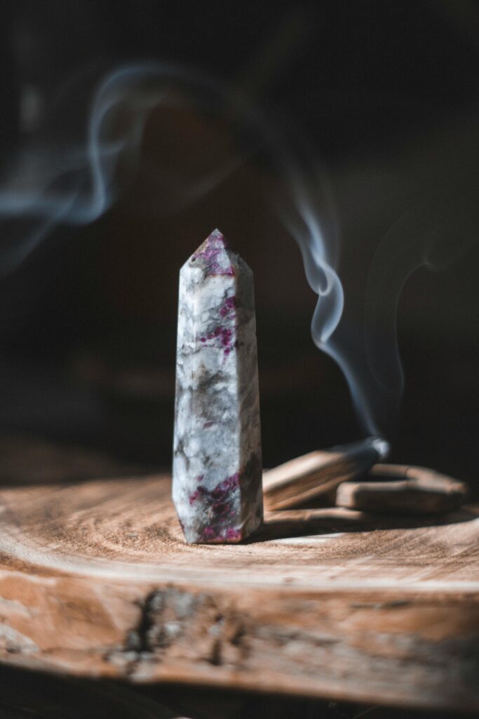 A smoky crystal mineral emits light smoke on a rustic wooden surface.